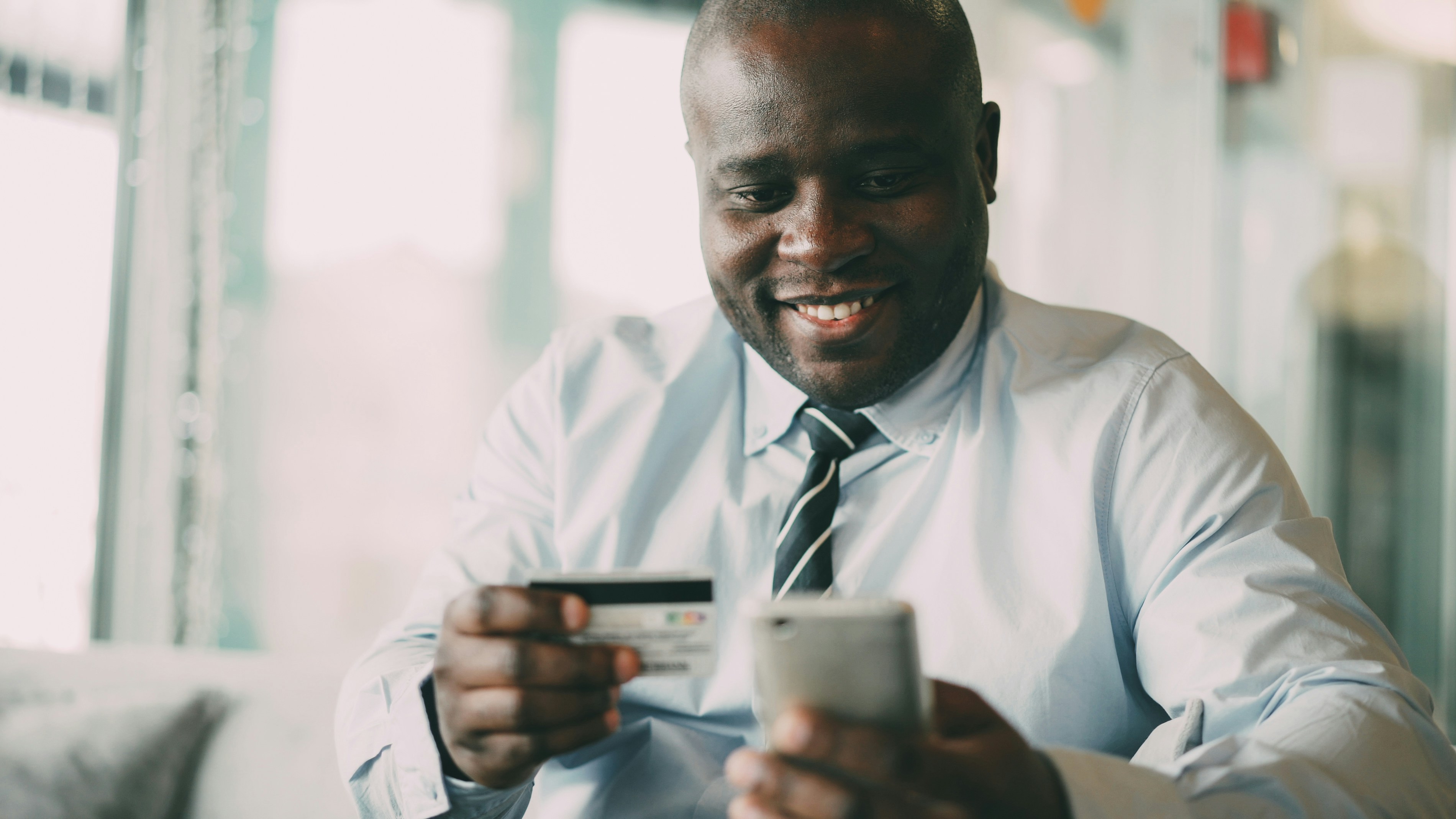 A parent checking his savings on his phone, card in hand